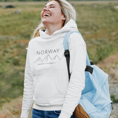 happy woman outdoors wearing white hoodie that has print with text Norway